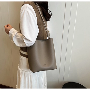 Detailed close-up of litchi grain texture and knotted strap on gray bucket bag