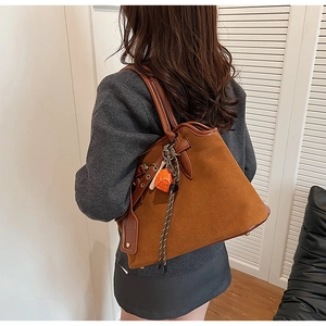 Detail view of retro brown tote bag with contrast leather trim and orange heart charm