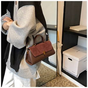 Sac bandoulière en cuir marron porté par un mannequin dans un décor épuré