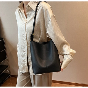 Detail of black lychee grain leather bucket bag with knot strap and gold metal ring