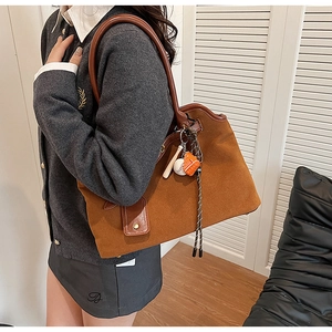 Detailed macro view of the brown frosted suede tote bag with a vintage baseball charm