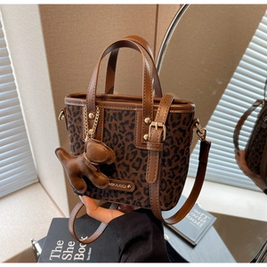 Détail du sac seau léopard avec garniture en cuir marron et accessoire de charme chiot