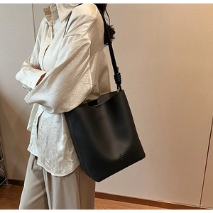 Detail of black pebbled leather bucket bag with a stylish knotted shoulder strap on model