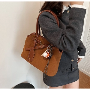 Detail of vintage matte brown tote bag with baseball themed charms and leather handles