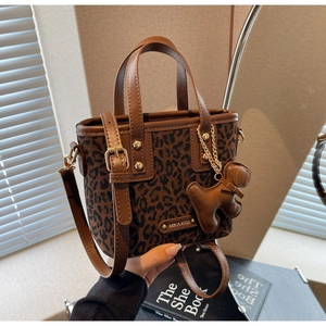 Détail du sac cabas léopard avec bordure en cuir marron et un charmant pendentif de chiot
