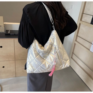 Close-up of metallic silver quilted tote bag with pink tassel and geometric strap
