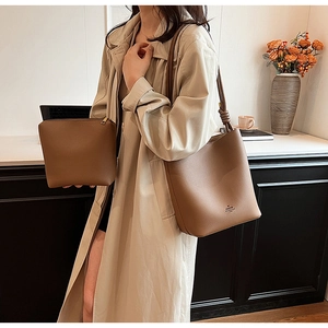 Detail of the brown bucket bag showing the unique knotted strap and pebbled leather texture