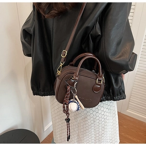Détail du sac bandoulière en cuir marron avec gaufrage TOUR et breloque baseball