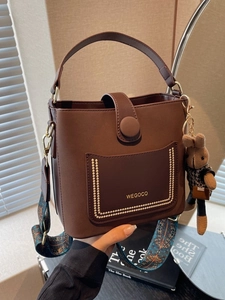 Brown leather bucket bag with wide ethnic strap and cute plush rabbit keychain charm