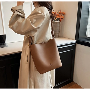 Detail view of deep brown litchi grain leather bucket bag with unique knotted strap