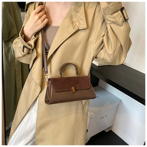 Detail of a dark brown PU leather crossbody bag featuring suede patchwork and gold buckle