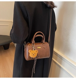 Detail of brown Boston pillow bag with cute plush bear charm and adjustable strap