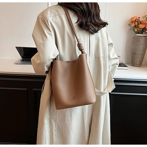 Lifestyle shot of a brown lychee pattern bucket bag with a stylish knotted shoulder strap