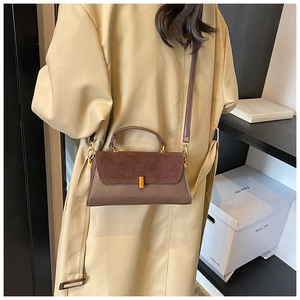 Brown patchwork crossbody bag with matte flap and metal lock worn with a trench coat