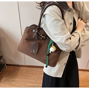 Detail of vintage matte suede tote bag in brown with baseball charm on beige jacket