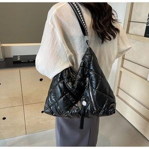 Quilted black puffer bag with diamond pattern and woven strap on model's shoulder