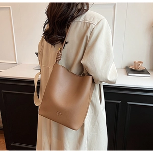Detail of a brown lychee pattern leather bucket bag with knotted shoulder strap