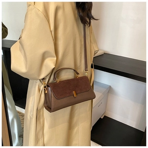 Sac à main vintage en daim marron porté avec un trench pour un look classique