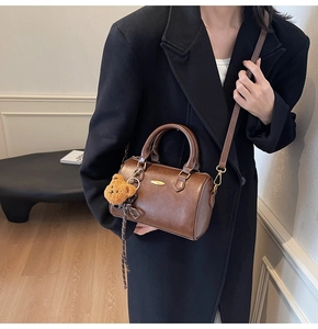 Detail of dark brown Boston bag featuring matte leather texture and cute bear charm accessory