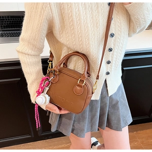 Détail d'un sac bandoulière marron vintage avec gaufrage SANTOUR et breloque baseball