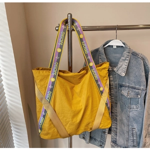 Détail du sac cabas jaune avec bandoulière à logo SJCHAO violet et nylon texturé