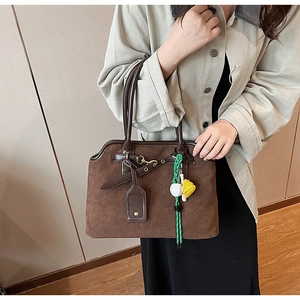 Close-up of vintage brown tote with suede texture and creative baseball bag charm