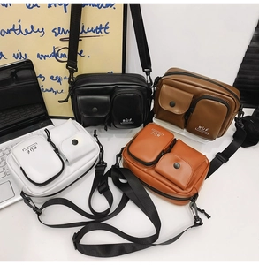 Detailed view of four colorful crossbody bags in black, brown, white and orange faux leather