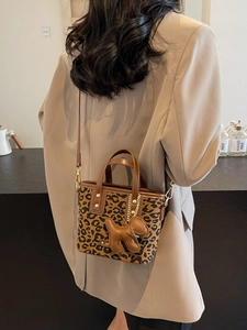 Sac seau léopard avec breloque chien et bandoulière en cuir porté par un mannequin