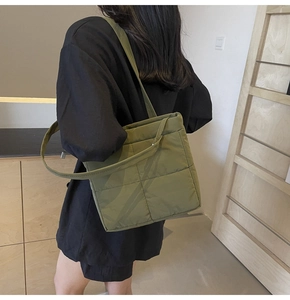 Detailed view of a grass green quilted tote bag worn by a model in a modern interior