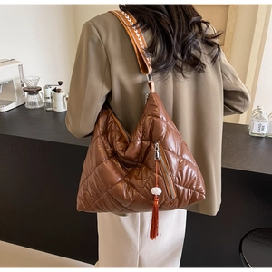 Detail of a brown quilted hobo bag with a patterned wide strap and tassel zipper