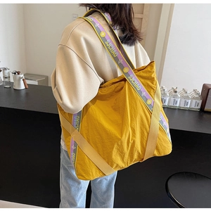 Détail d'un grand sac cabas jaune vif montrant le tissu en nylon et la sangle décorée