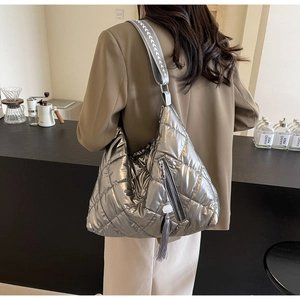 Detail of silver metallic quilted hobo bag with fringe charms and woven shoulder strap
