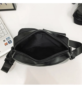 Top view of black crossbody bag showing internal compartment with zipper on a desk