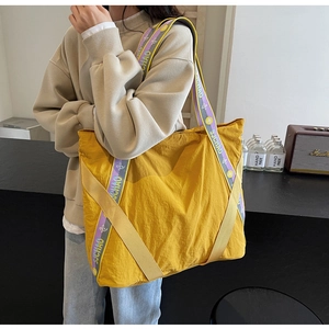 Gros plan d'un grand sac cabas en nylon jaune avec une bandoulière décorative en jacquard