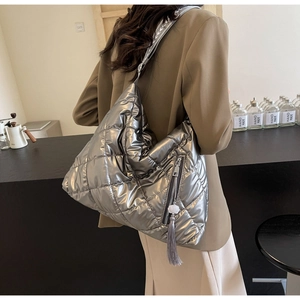 Detail of silver quilted tote bag featuring metallic finish and decorative side tassel