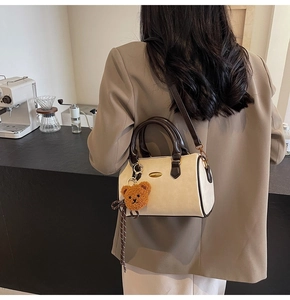 Chic beige boston bag with brown leather handles and cute plush bear charm on side