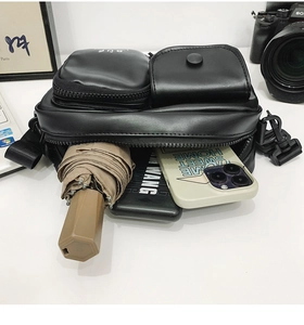 Detailed view showing storage capacity of black tactical crossbody bag with daily essentials