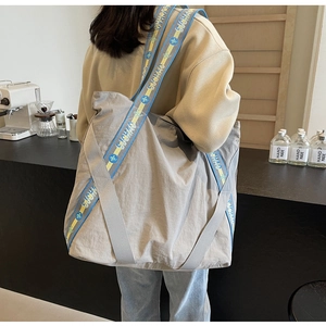 Gros plan d'un grand sac cabas en nylon gris avec des poignées tissées colorées au café