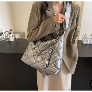 Detail of silver quilted puffer bag with woven shoulder strap and tassel zipper