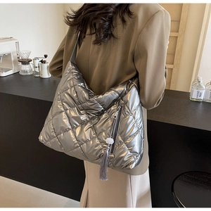 Silver quilted tote bag detail with tassel and flower charm in casual setting