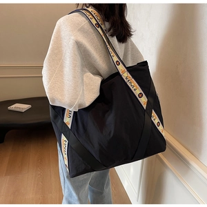 Détail d'un grand sac cabas en toile noire avec des bandoulières à motifs géométriques