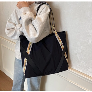 Détail du sac cabas noir avec des sangles tissées crème et des motifs d'étoiles