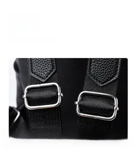 Detailed macro view of silver metal adjustment buckle on black lychee leather backpack