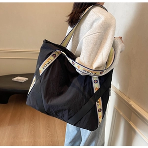 Vue macro du grand sac cabas noir en nylon avec bandoulière tissée à logo coloré
