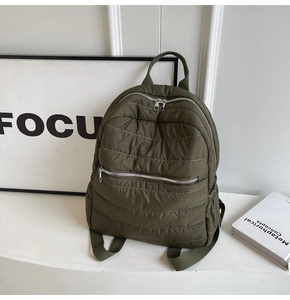 Detail of olive green quilted puffer backpack showing glossy water-resistant nylon texture