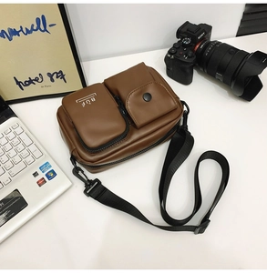 Detail of dark brown crossbody bag with dual front pockets and removable nylon strap