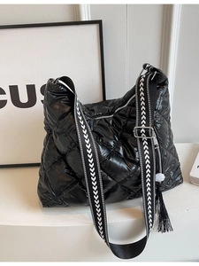 Quilted down fabric tote bag in black featuring wide geometric strap and fringe detail