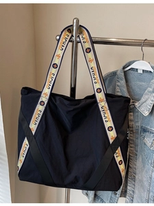 Grand sac cabas noir avec bandoulière jacquard géométrique colorée suspendu à un cintre
