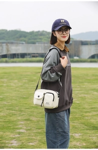Outdoor shot of a beige functional crossbody phone bag with adjustable shoulder strap
