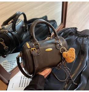 Detail of dark brown Boston bag featuring gold hardware and a cute plush bear charm